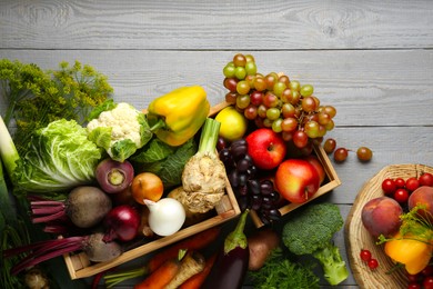 Photo of Different fresh vegetables and fruits in crates on grey wooden table, flat lay. Farmer harvesting