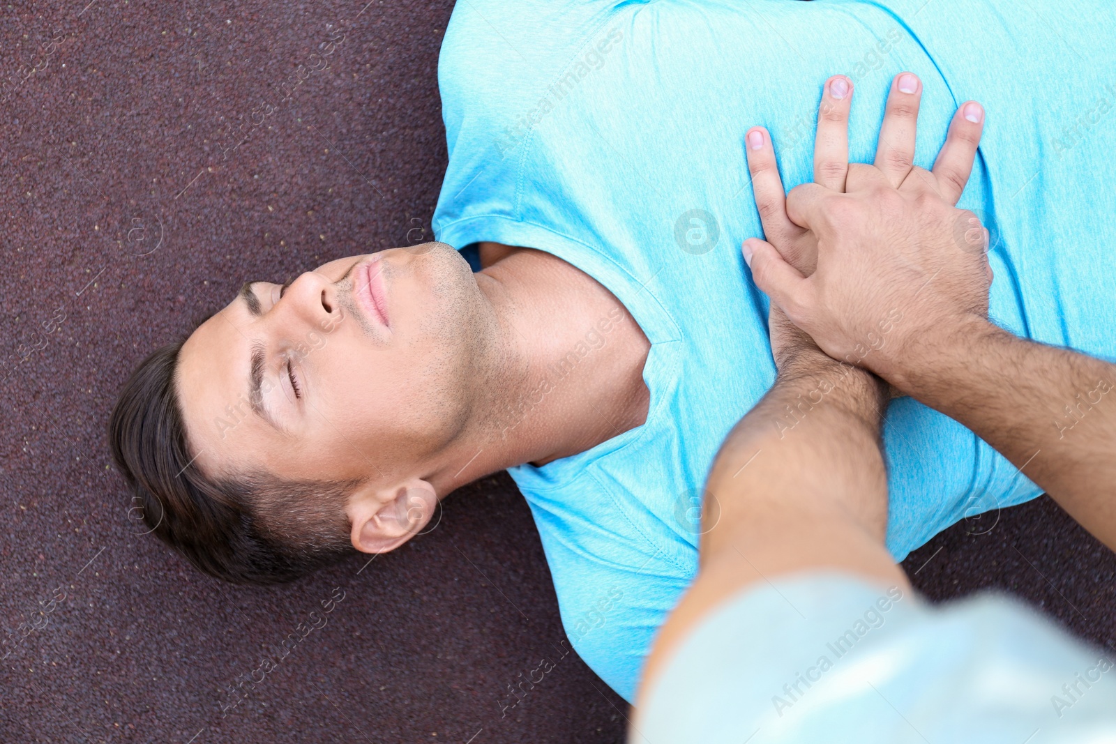 Photo of Passerby performing CPR on unconscious man outdoors, top view. First aid