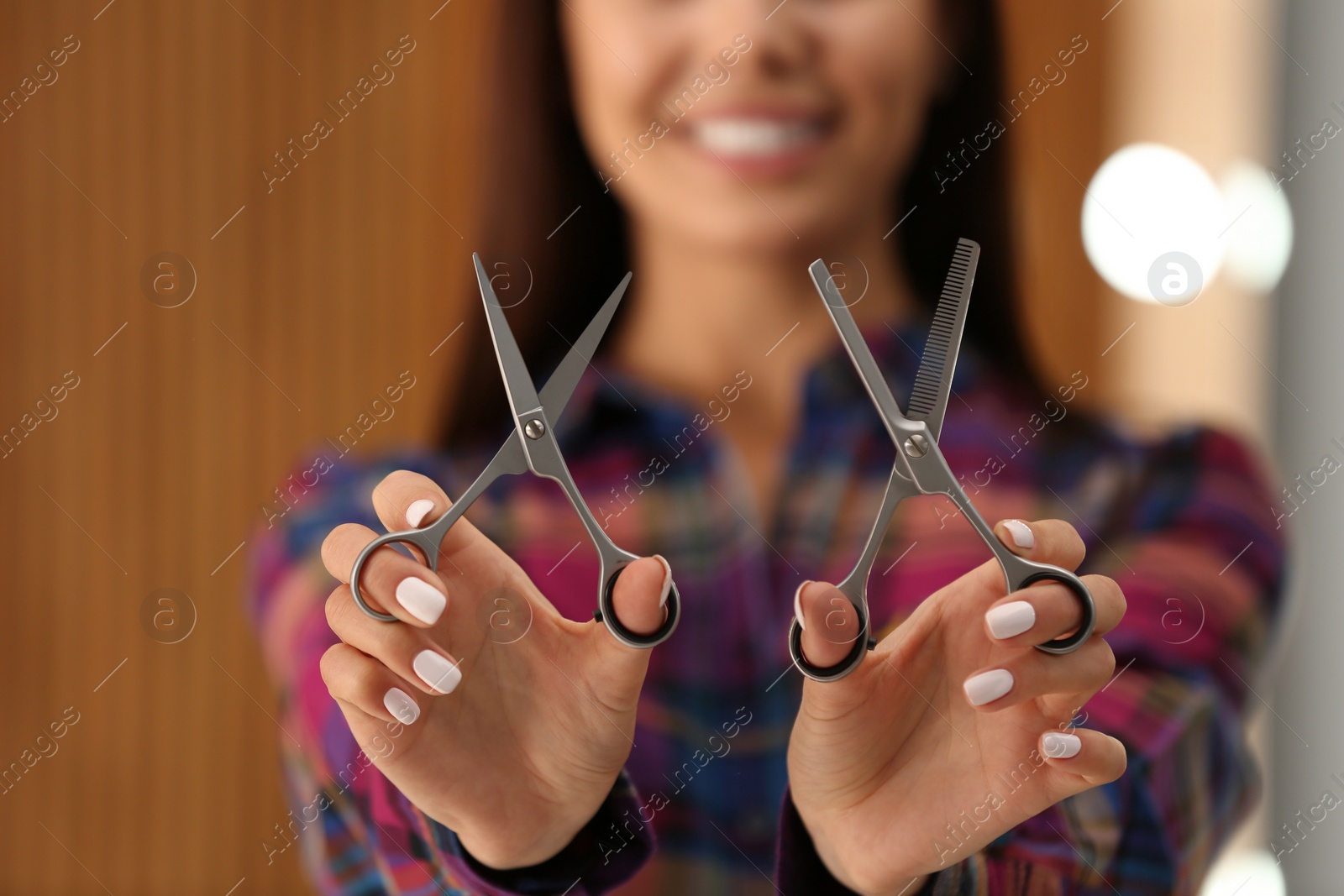 Photo of Hairstylist holding professional scissors in beauty salon, closeup