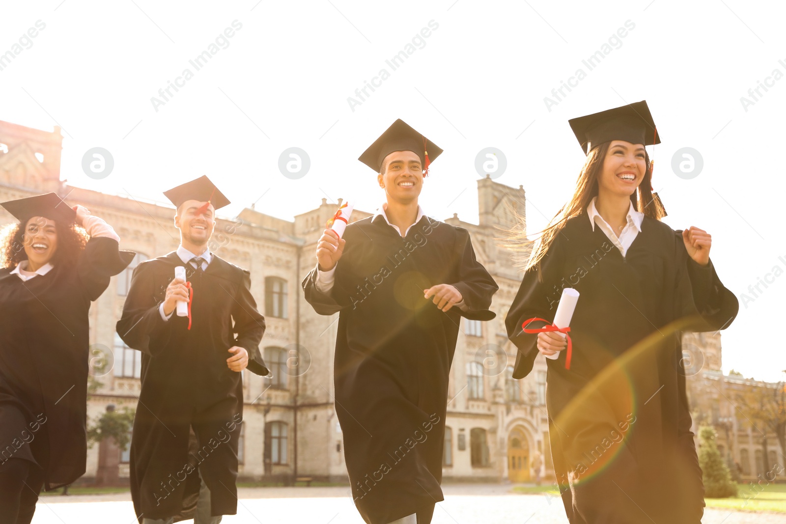 Photo of Happy students with diplomas outdoors. Graduation ceremony