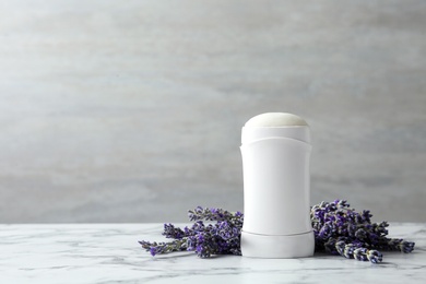 Female deodorant and lavender flowers on white marble table. Space for text