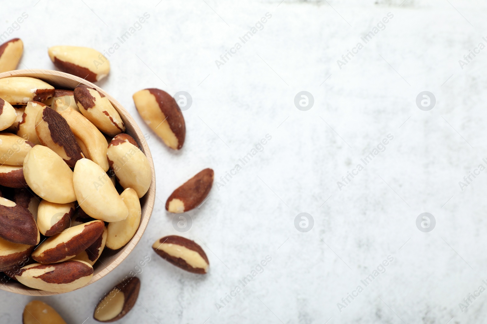 Photo of Delicious Brazil nuts on white table, flat lay. Space for text