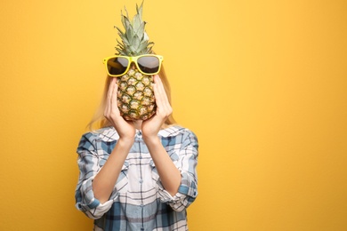 Photo of Woman holding pineapple with sunglasses on color background