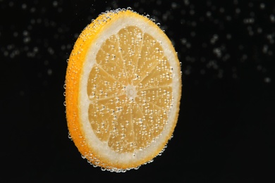 Slice of lemon in sparkling water on black background. Citrus soda