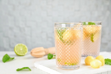 Photo of Glasses with tasty melon ball drink on table. Space for text