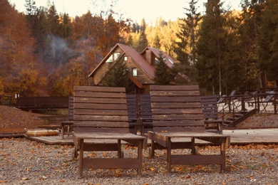 Resort with wooden sunbeds near forest on sunny autumn day