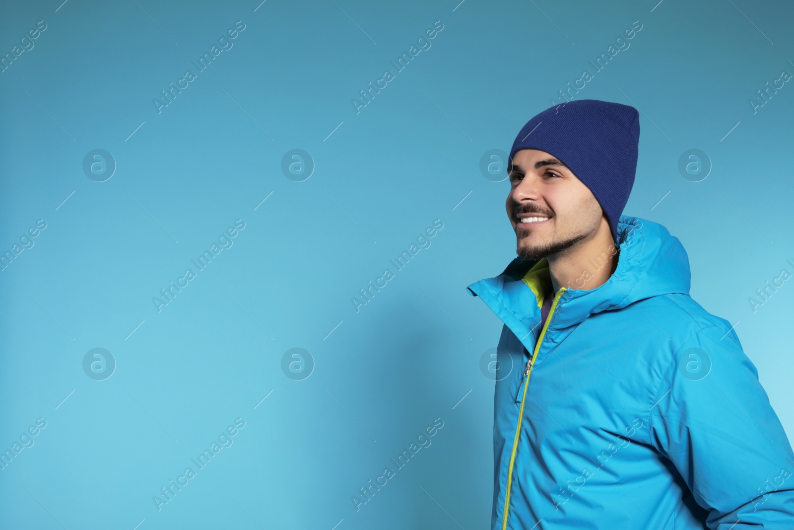 Photo of Young man wearing warm clothes on color background, space for text. Ready for winter vacation