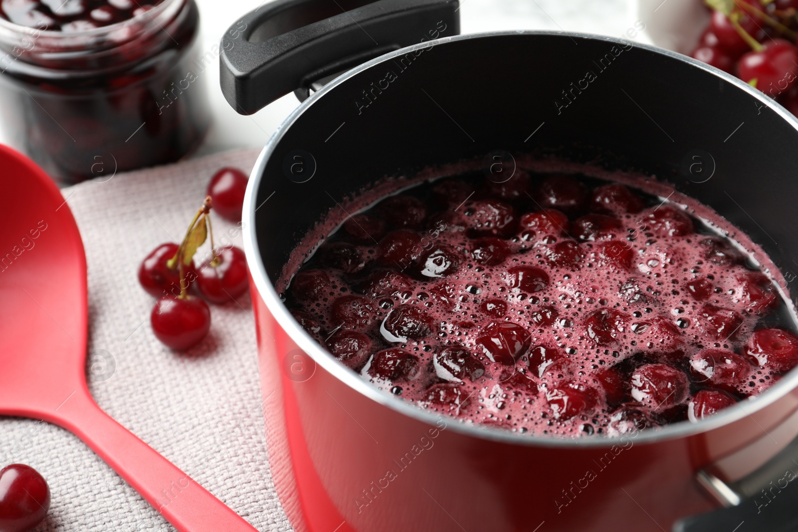 Photo of Pot with cherries in sugar syrup on table, closeup. Making delicious jam