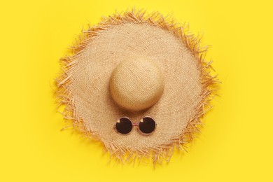 Photo of Straw hat and sunglasses on yellow background, flat lay. Stylish headdress