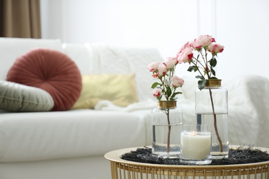 Photo of Burning candle and vases with beautiful roses on table indoors, space for text. Interior elements