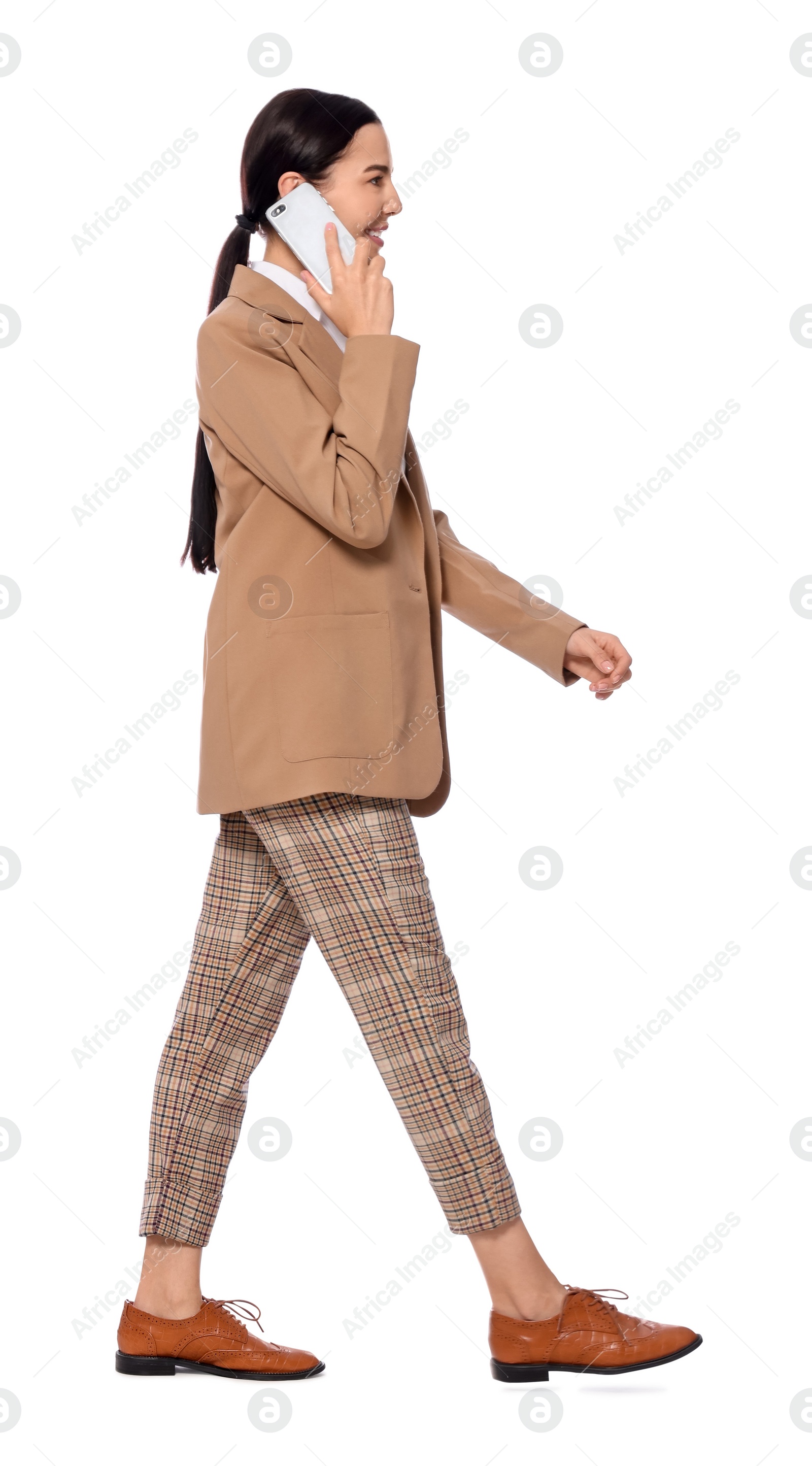 Photo of Young businesswoman talking on smartphone while walking against white background