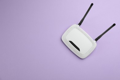 Modern Wi-Fi router on lilac background, top view. Space for text