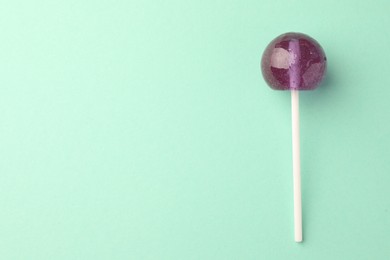 Photo of Tasty lollipop on turquoise background, top view. Space for text