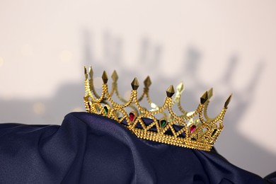 Photo of Beautiful golden crown with gems on dark blue cloth