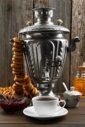 Photo of Composition with hot tea and delicious ring shaped Sushki (dry bagels) on wooden table