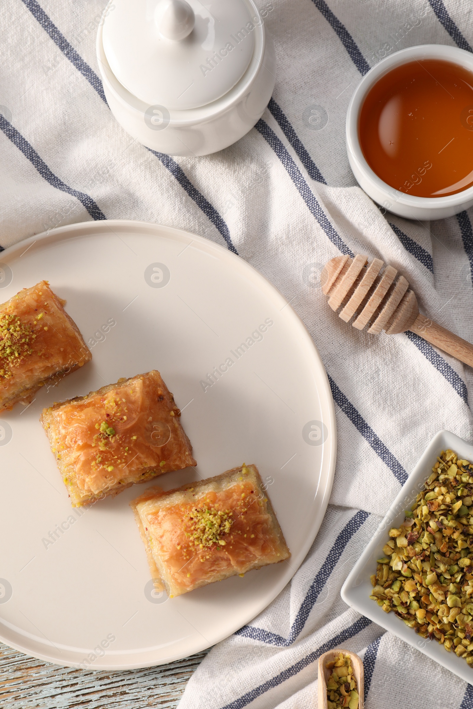 Photo of Delicious sweet baklava with nuts and honey on table, flat lay