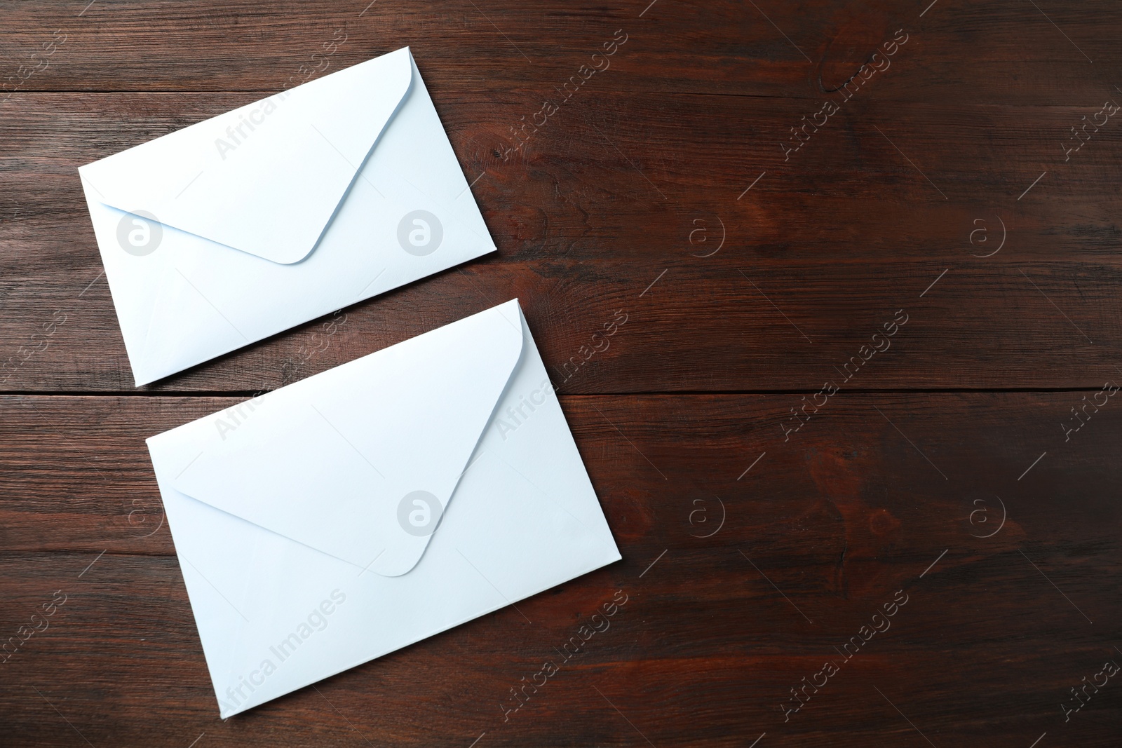 Photo of White paper envelopes on wooden table. Space for text