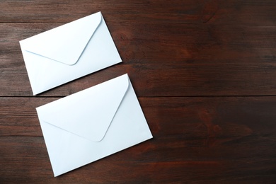 Photo of White paper envelopes on wooden table. Space for text