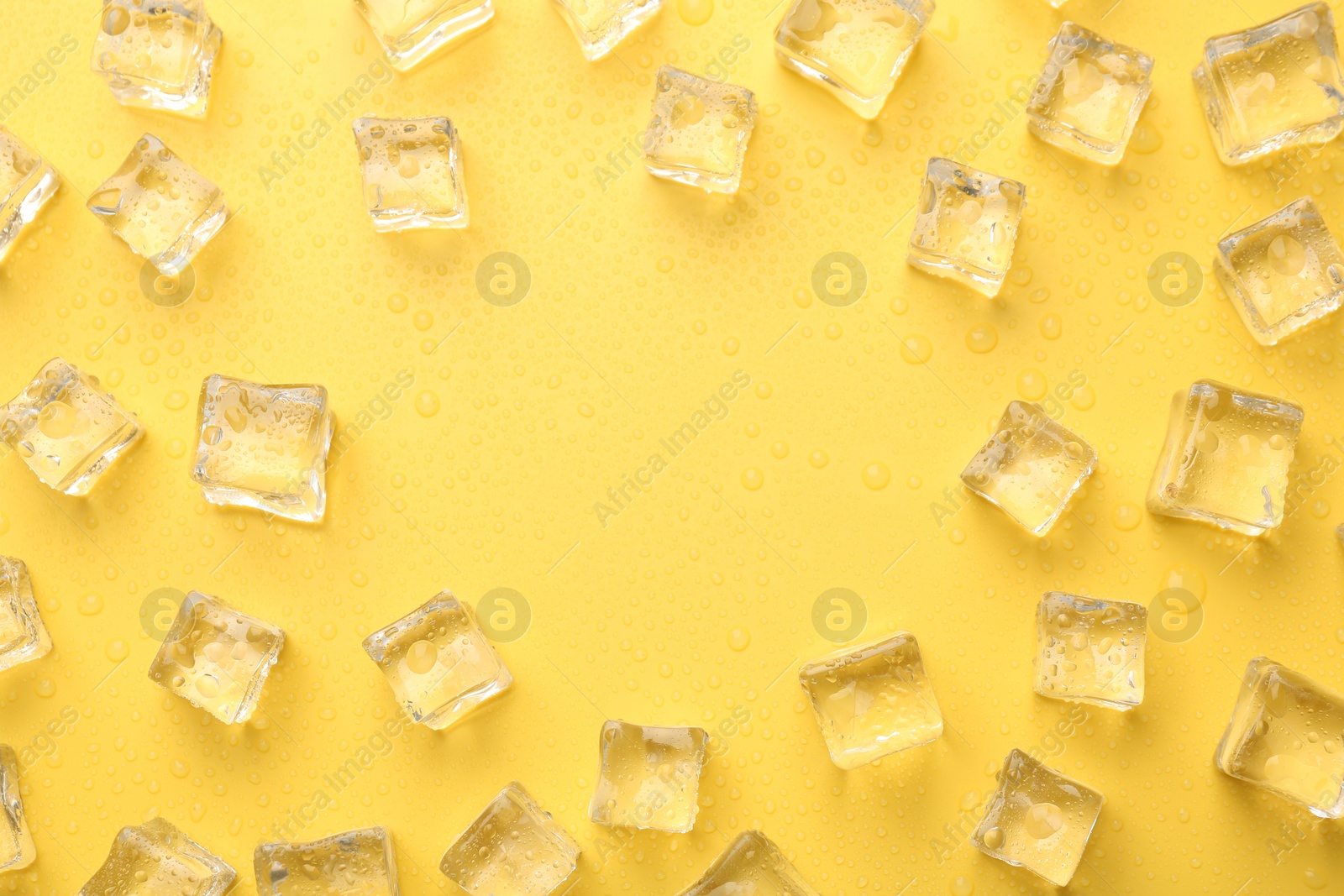 Photo of Crystal clear ice cubes on yellow background, flat lay. Space for text