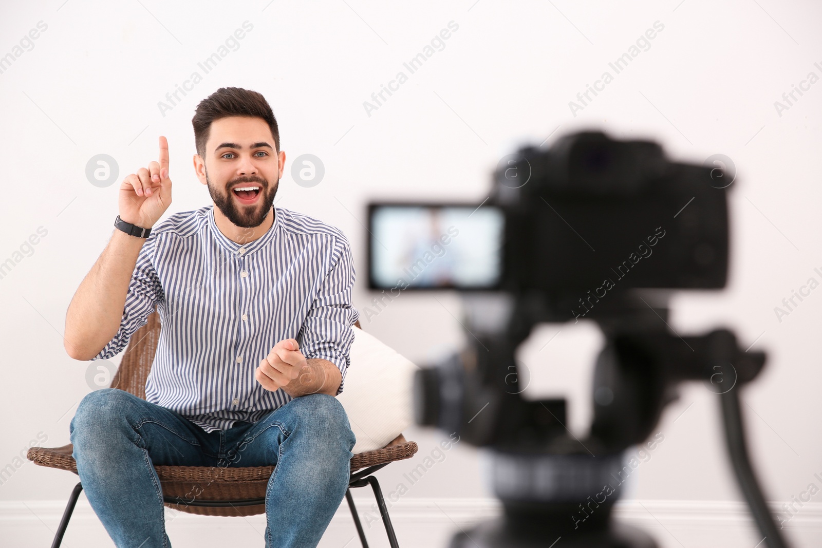 Photo of Young blogger recording video on camera indoors