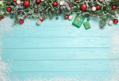 Flat lay composition with fir branches, Christmas decoration and snow on light blue wooden background. Space for text