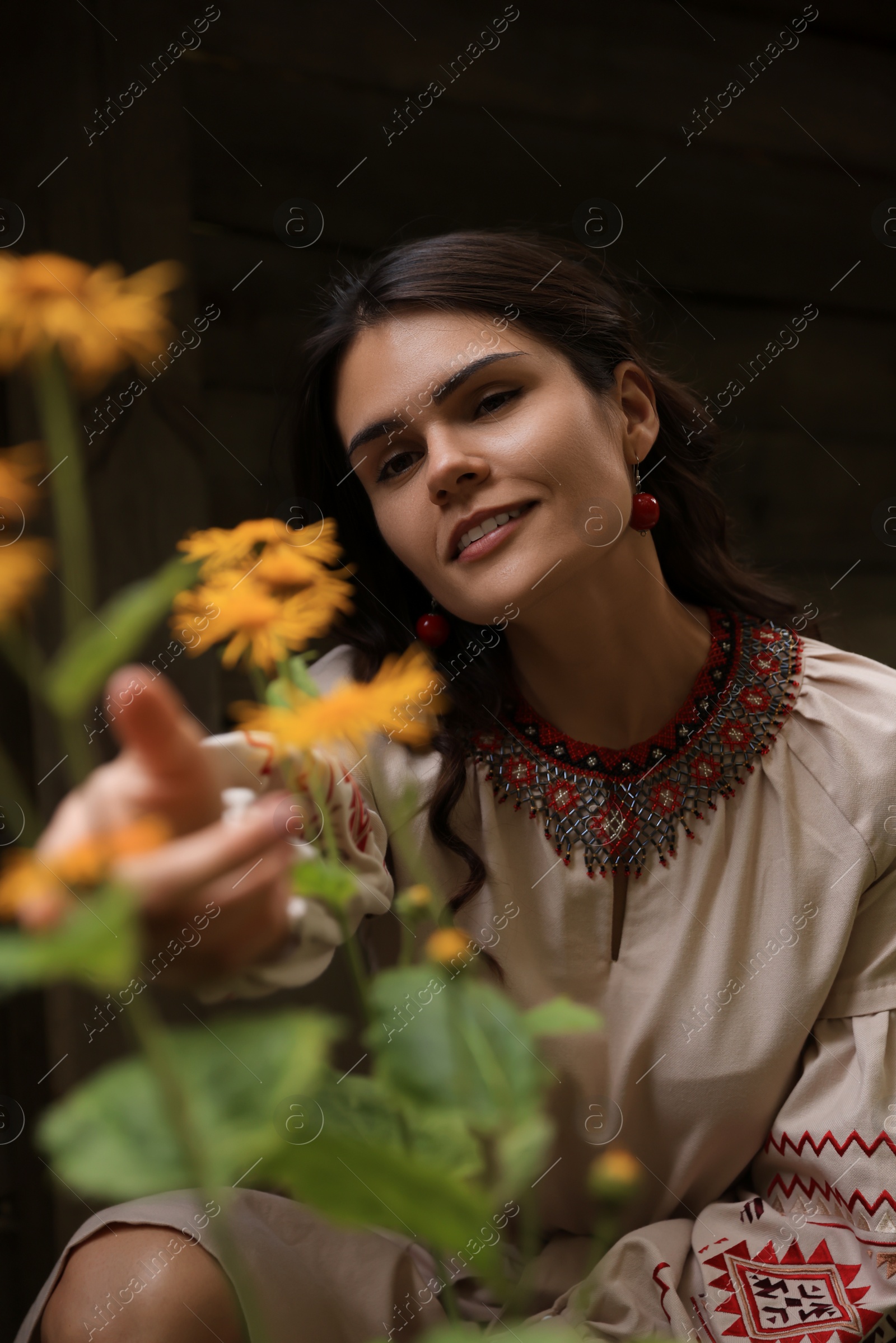 Photo of Beautiful woman wearing embroidered dress in blooming garden. Ukrainian national clothes