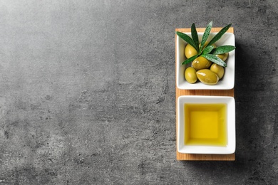 Dishes with olive oil and ripe olives on table, top view