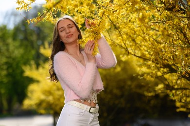 Beautiful young woman near blossoming shrub on spring day, space for text