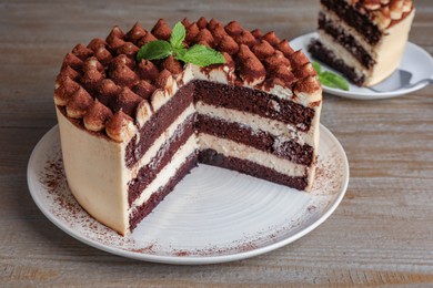 Photo of Delicious tiramisu cake with mint leaves on wooden table
