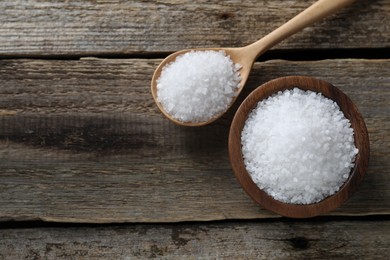 Photo of Organic salt in bowl and spoon on wooden table, flat lay. Space for text