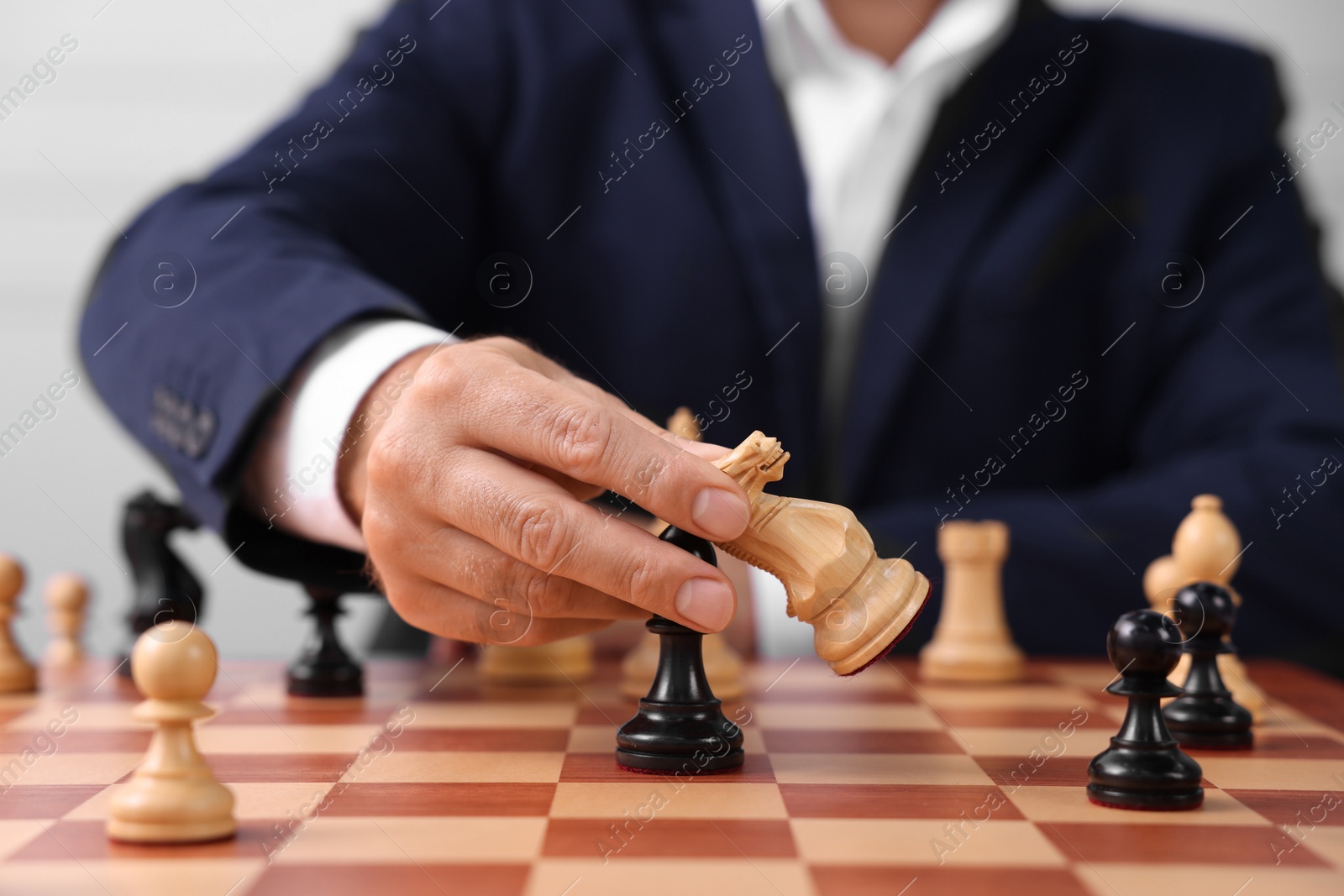 Photo of Man with game pieces playing chess at checkerboard, closeup