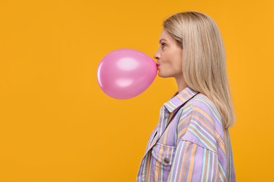 Photo of Woman blowing up balloon on yellow background. Space for text