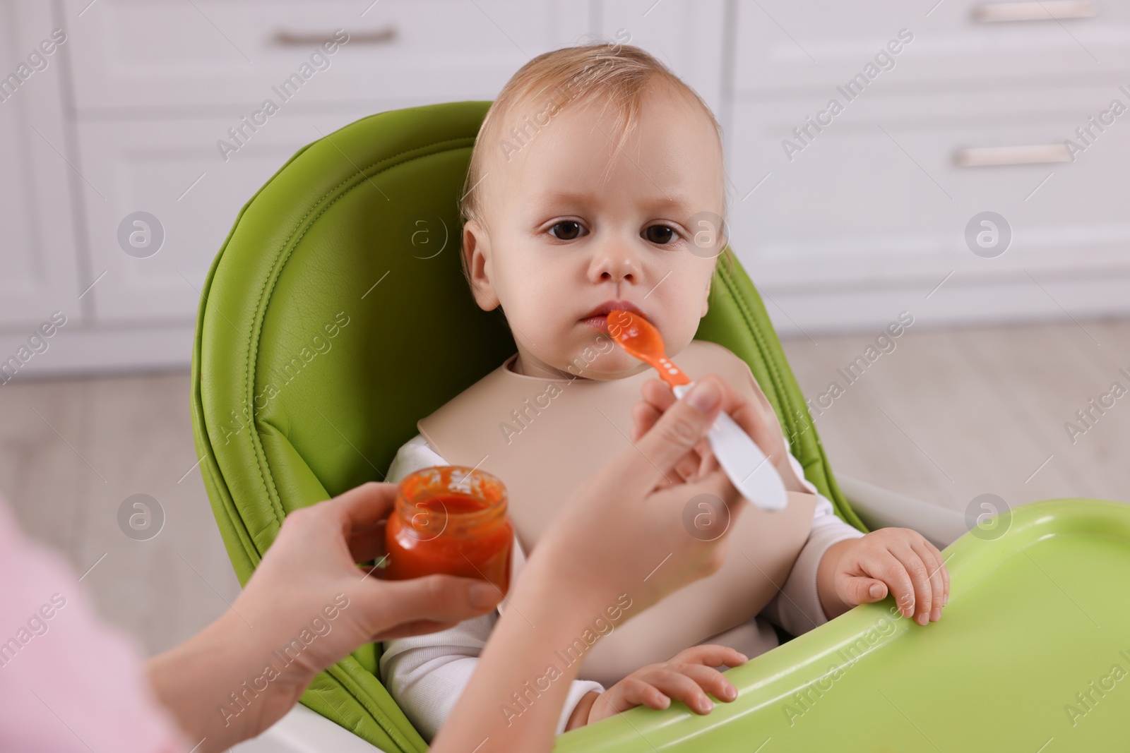 Photo of Mother feeding her cute little baby with healthy food at home