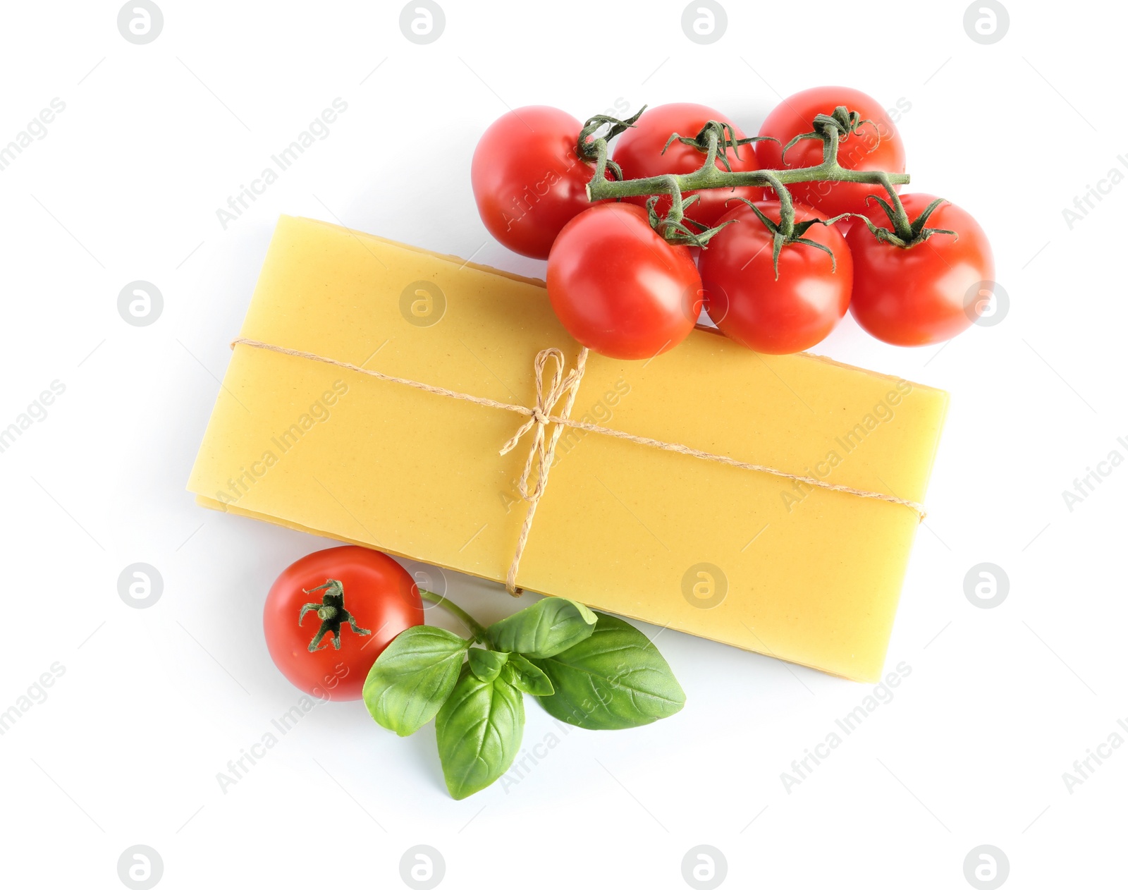 Photo of Uncooked lasagna sheets, tomatoes and basil on white background, top view