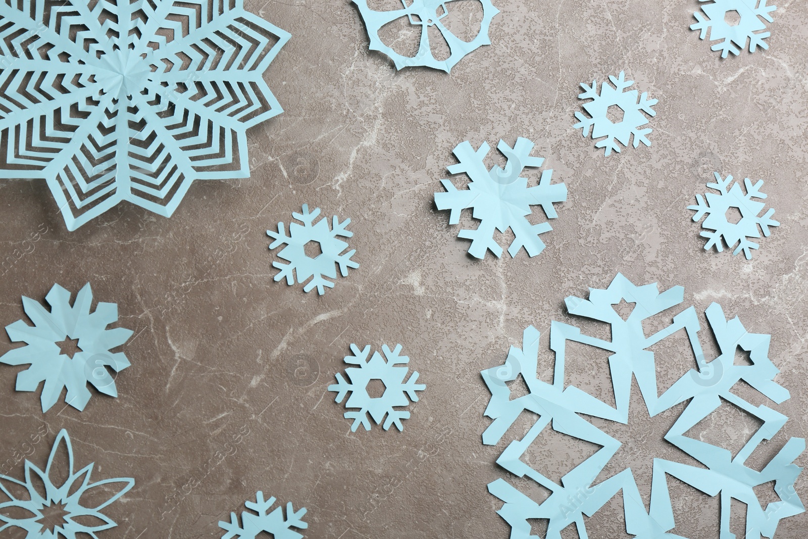 Photo of Many paper snowflakes on grey background, flat lay