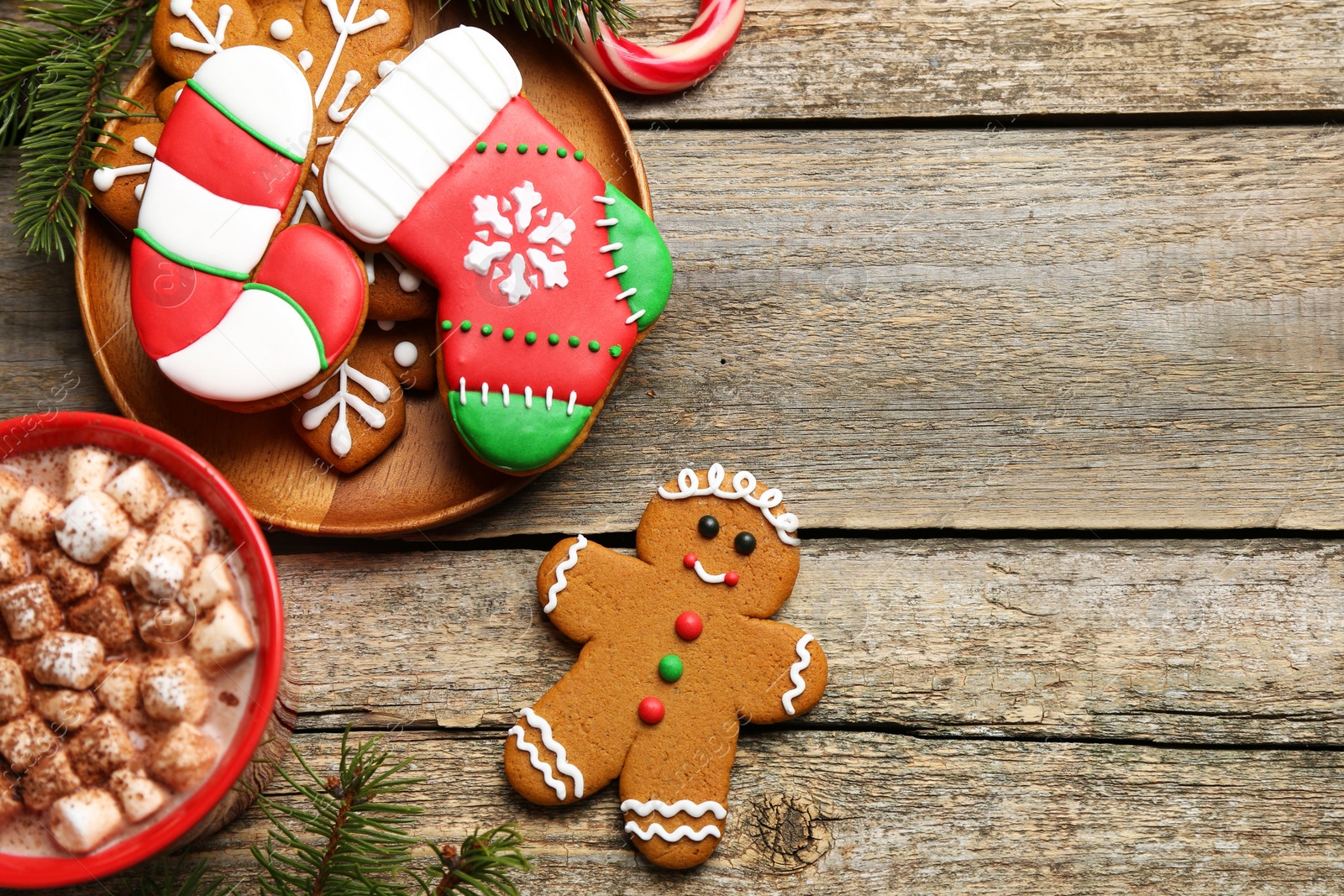 Photo of Different tasty Christmas cookies, decor and cocoa with marshmallows on wooden table, flat lay. Space for text