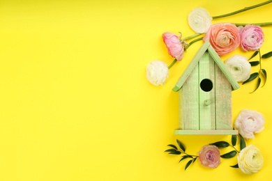 Photo of Stylish bird house and fresh eustomas on yellow background, flat lay. Space for text