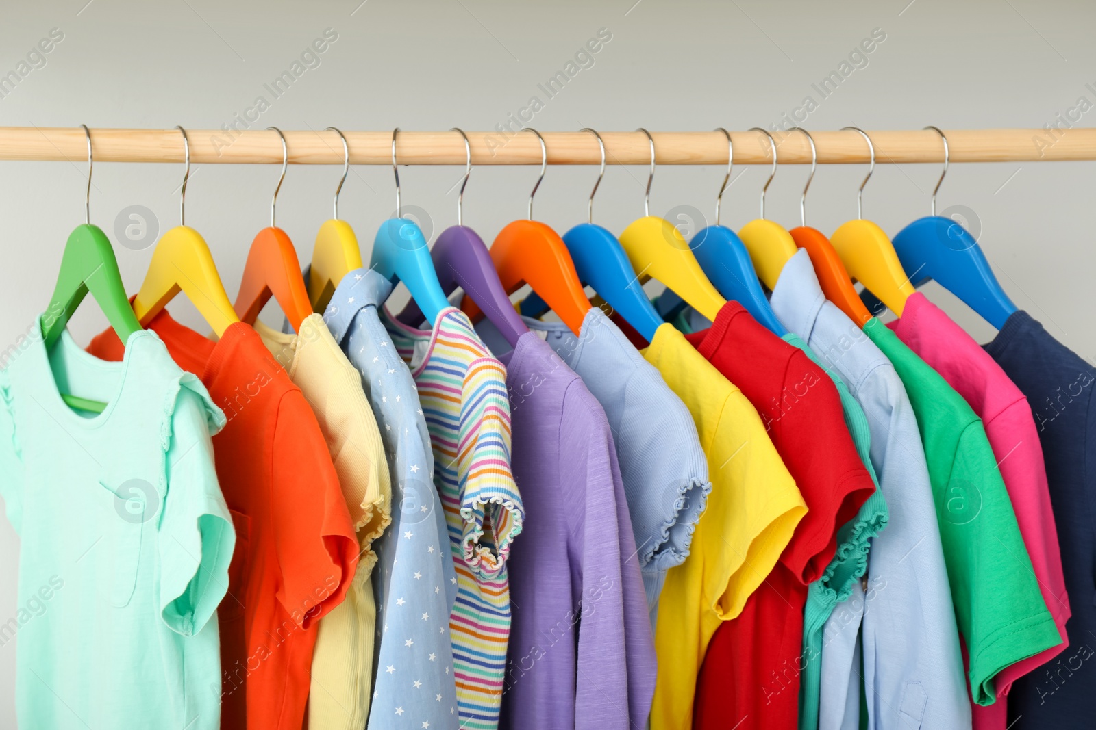 Photo of Rack with different clothes on light background, closeup