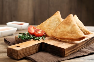 Fresh delicious crispy samosas served on wooden table