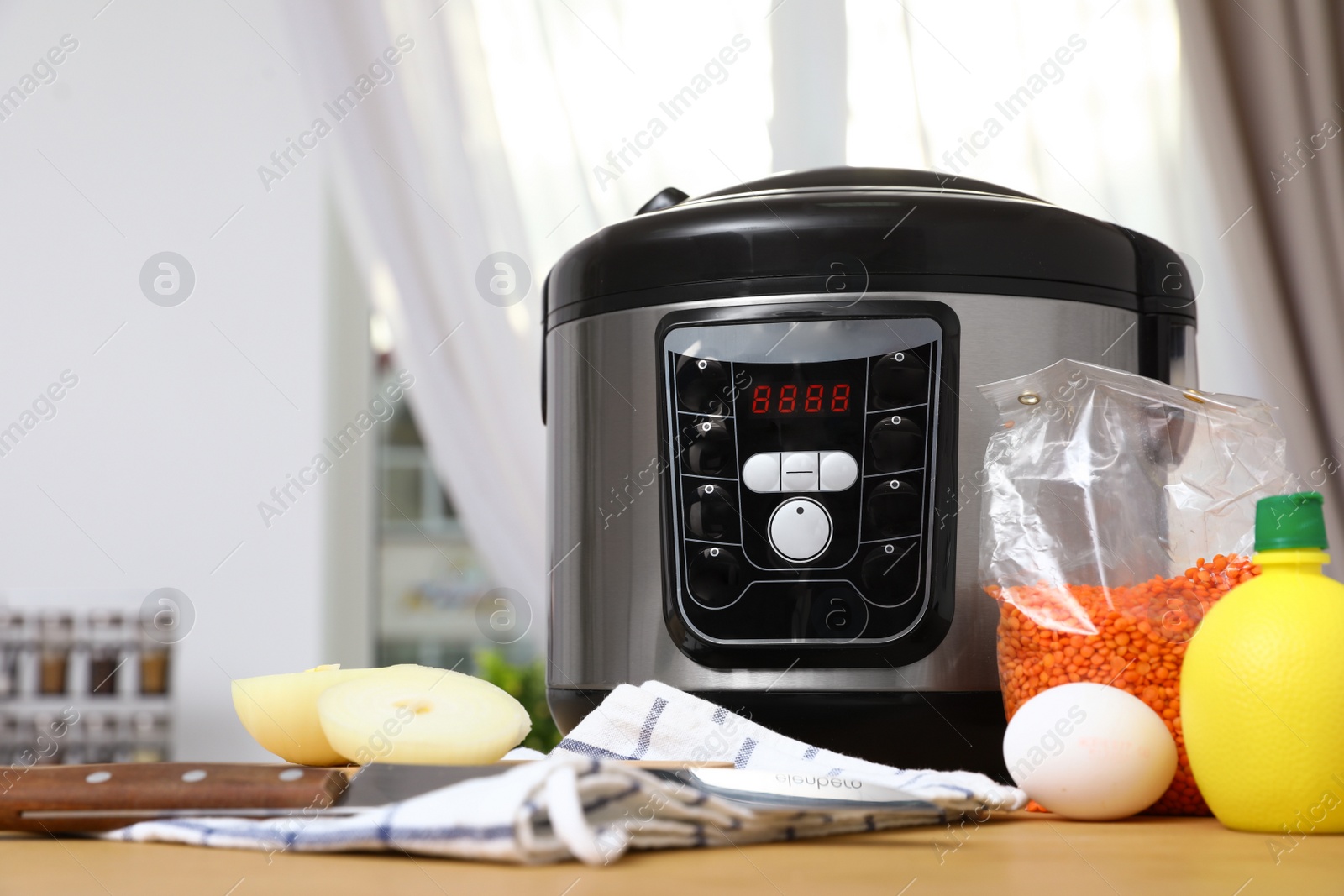 Photo of New modern multi cooker and products on table in kitchen. Space for text
