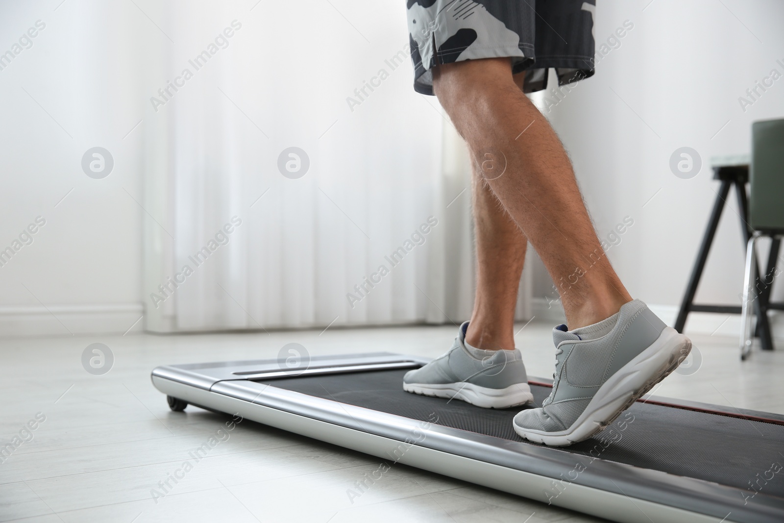 Photo of Sporty man training on walking treadmill at home, closeup