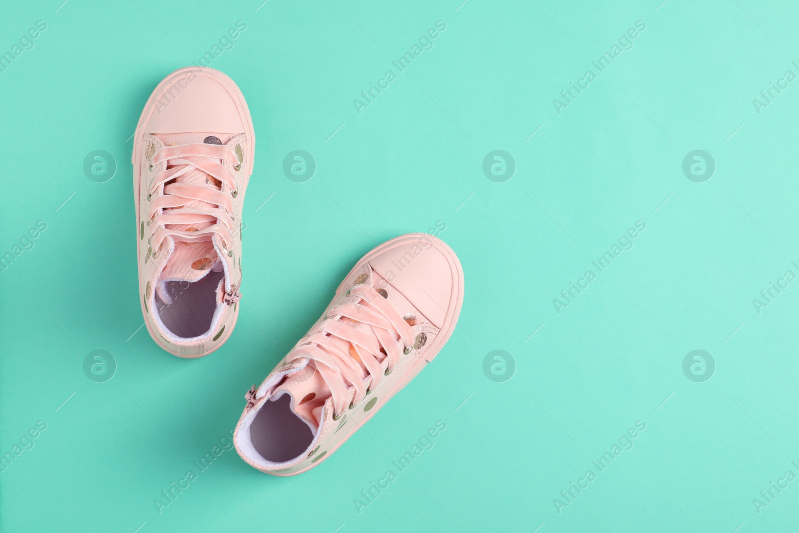 Photo of Pair of stylish child shoes on turquoise background, flat lay. Space for text