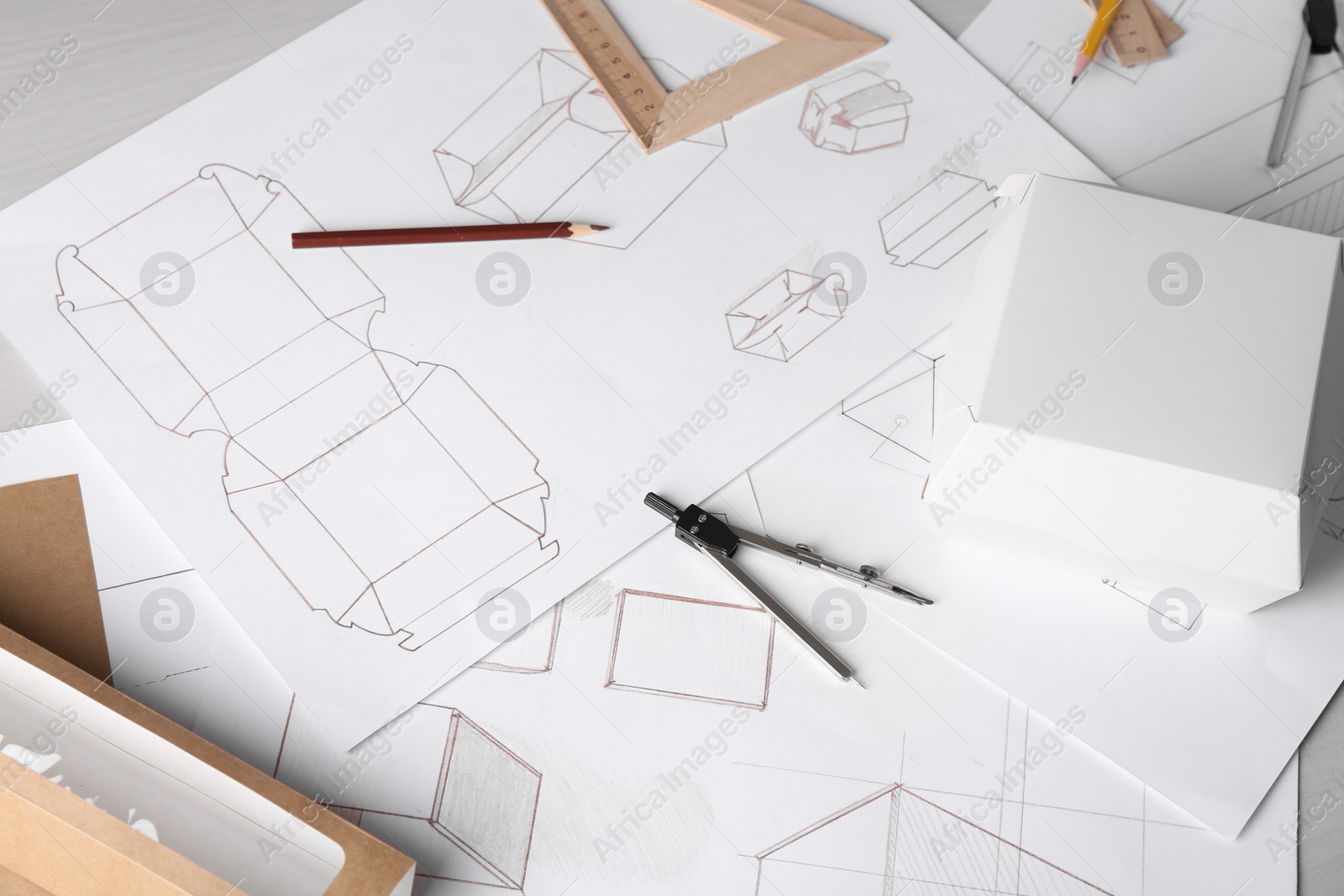 Photo of Creating packaging design. Drawings, boxes and stationery on light wooden table, above view