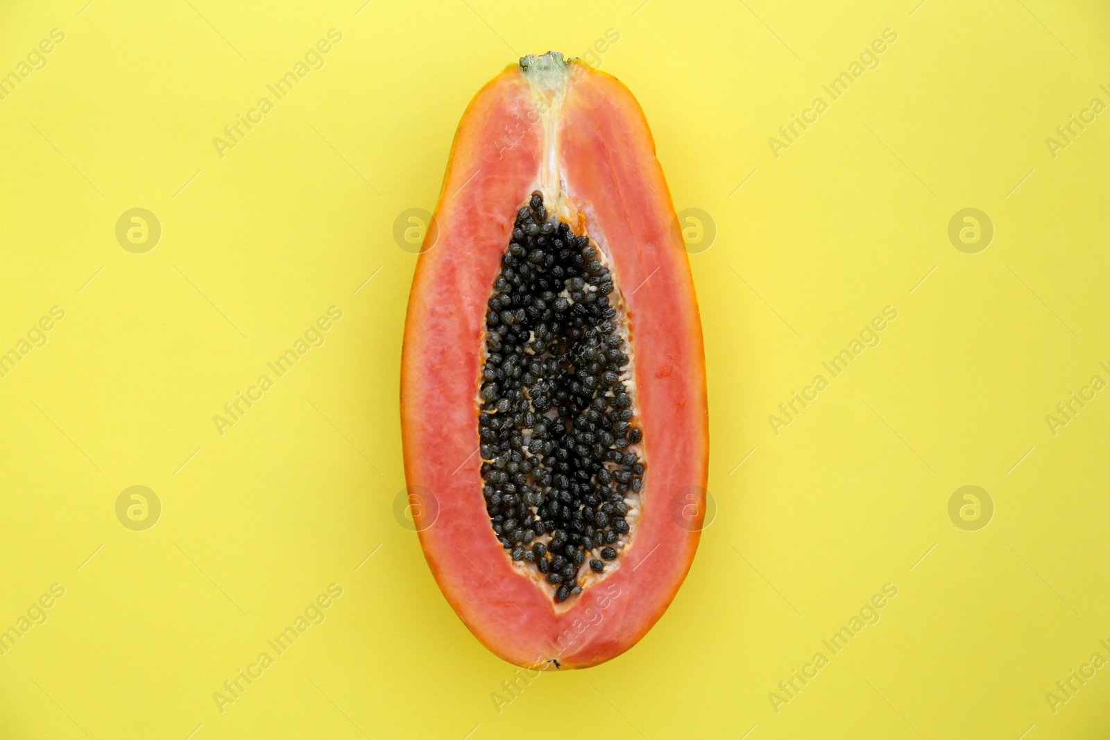 Photo of Half of fresh ripe papaya fruit on light green background, top view