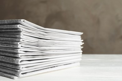 Photo of Stack of newspapers on white wooden table. Journalist's work