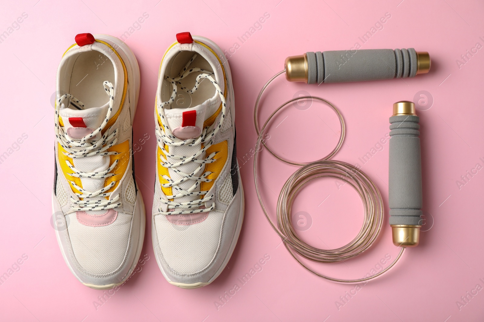 Photo of Jump rope and sneakers on color background. Healthy lifestyle