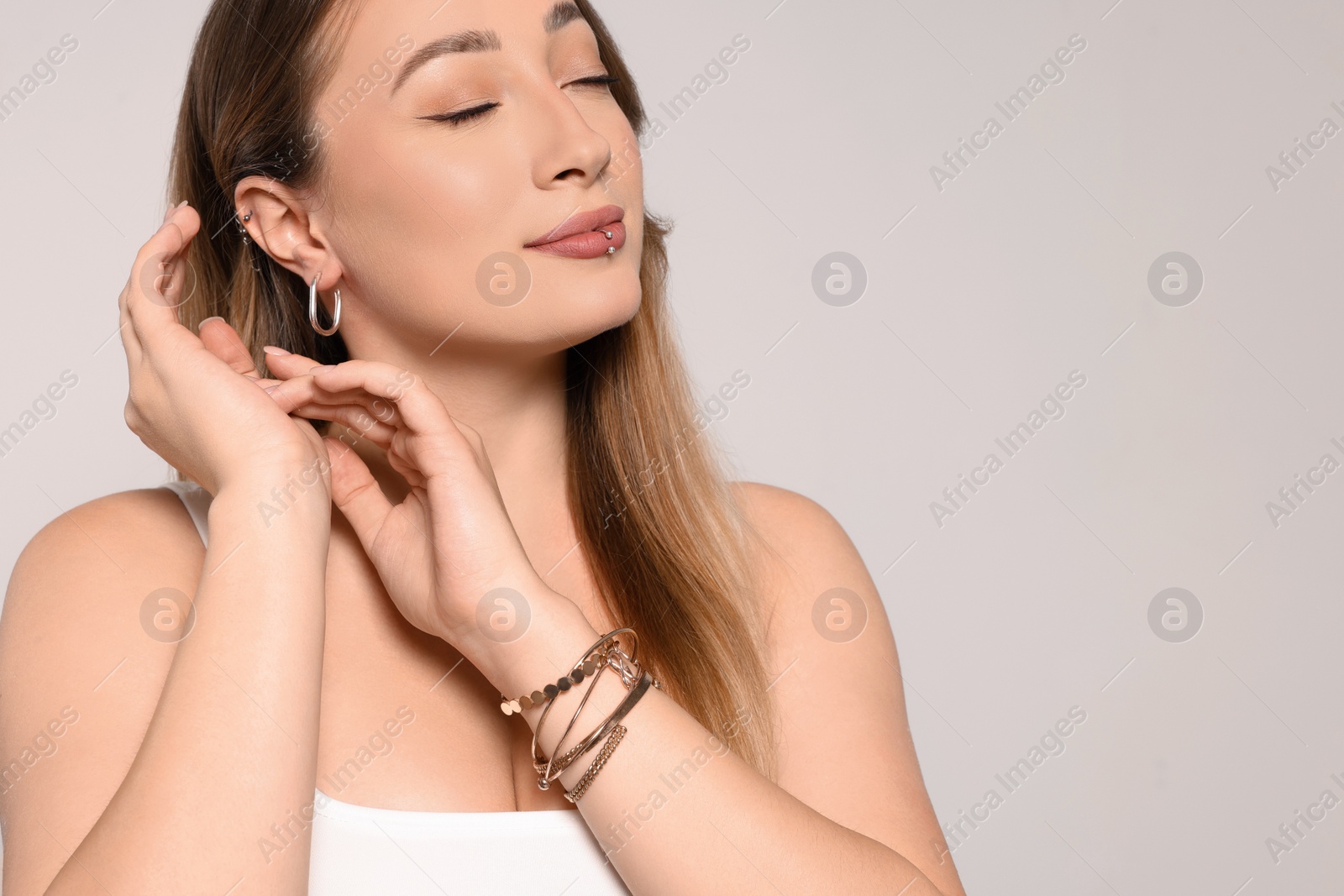 Photo of Young woman with lip and ear piercings on white background, space for text