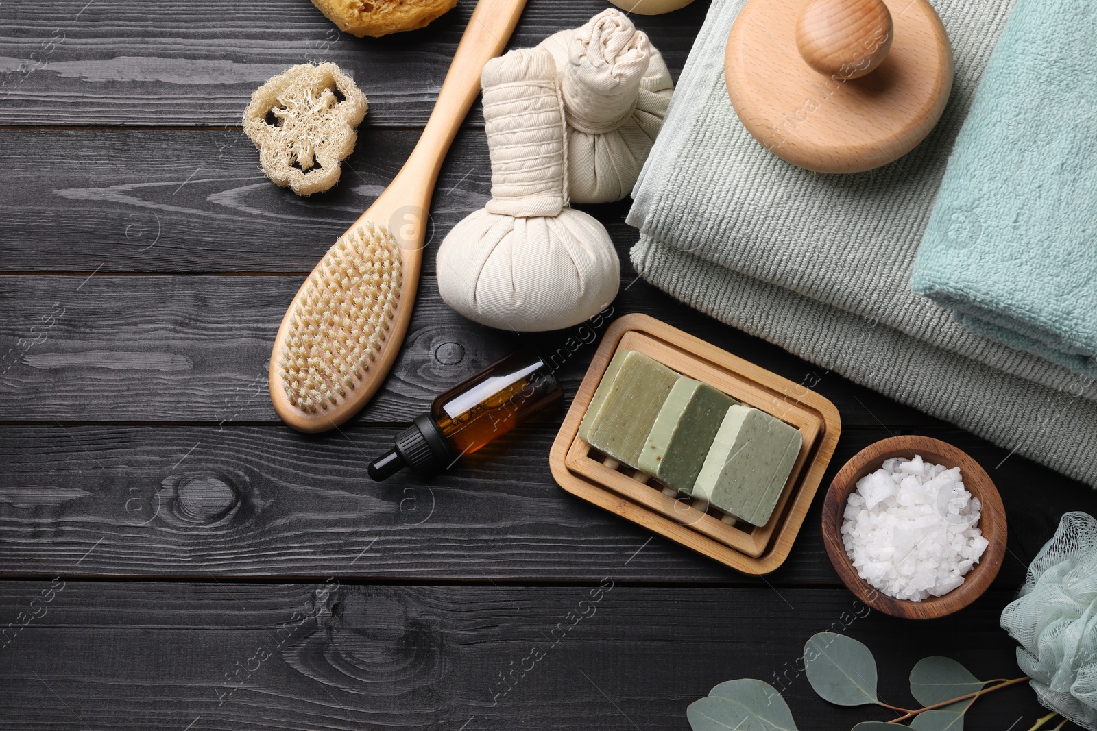 Photo of Flat lay composition with different spa products and eucalyptus branches on black wooden table. Space for text