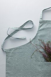 Photo of Clean kitchen apron with beautiful flowers on light grey background, top view