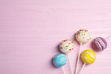 Bright delicious cake pops on wooden table, flat lay. Space for text